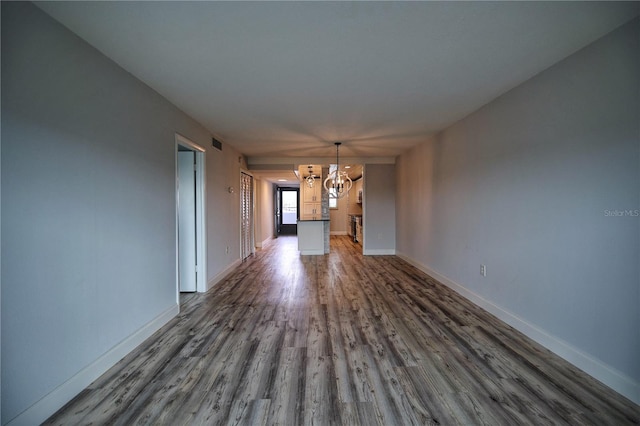 unfurnished living room with dark wood-type flooring and a notable chandelier