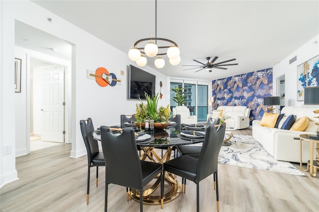 dining space with ceiling fan with notable chandelier and light hardwood / wood-style floors