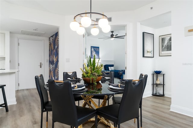 dining space featuring ceiling fan with notable chandelier and light hardwood / wood-style flooring