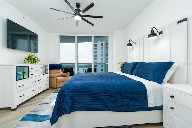 bedroom featuring light hardwood / wood-style flooring, expansive windows, access to exterior, and ceiling fan