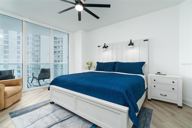 bedroom featuring a wall of windows, access to exterior, ceiling fan, and light hardwood / wood-style floors