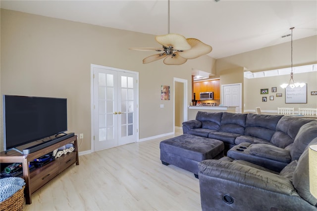 living room featuring light hardwood / wood-style flooring, ceiling fan with notable chandelier, and french doors