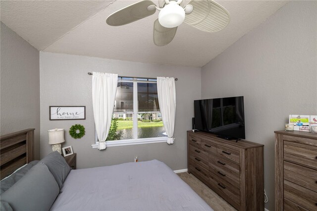 carpeted bedroom featuring lofted ceiling, ceiling fan, and a textured ceiling