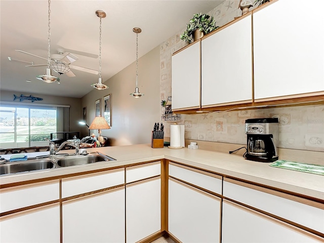 kitchen featuring white cabinetry, sink, decorative backsplash, and hanging light fixtures