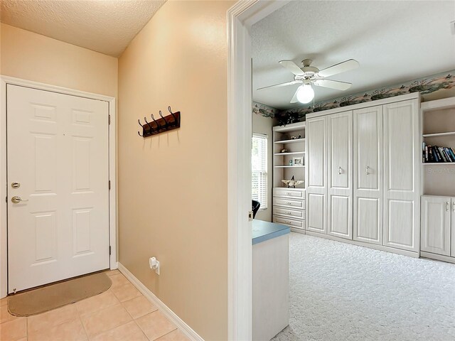 carpeted foyer featuring a textured ceiling and ceiling fan