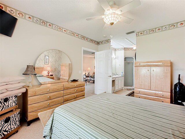 bedroom featuring light colored carpet, ensuite bathroom, and ceiling fan