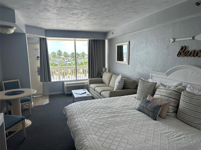 carpeted bedroom featuring a textured ceiling and a wall mounted air conditioner