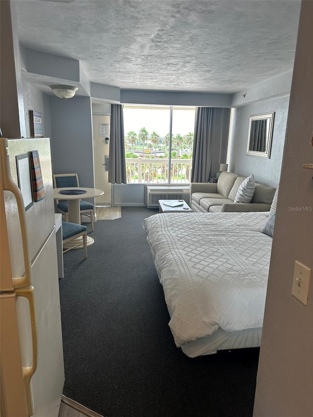 2700 N Atlantic Ave Unit 423, Daytona Beach, FL 32118 - bedroom featuring freestanding refrigerator, carpet, a textured ceiling, and a wall unit AC