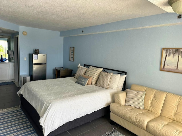 bedroom with a textured ceiling and stainless steel fridge