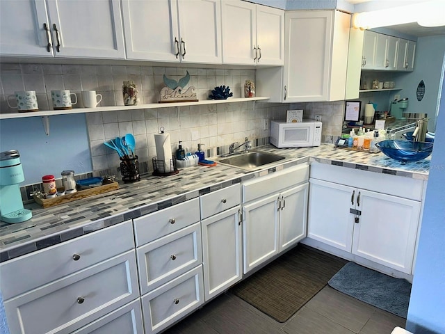 2700 N Atlantic Ave Unit 433, Daytona Beach, FL 32118 - kitchen with open shelves, white microwave, white cabinets, and tasteful backsplash