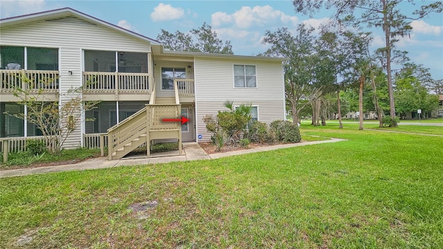 rear view of property featuring a lawn and stairs