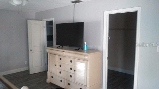 bedroom with a spacious closet and dark wood-type flooring