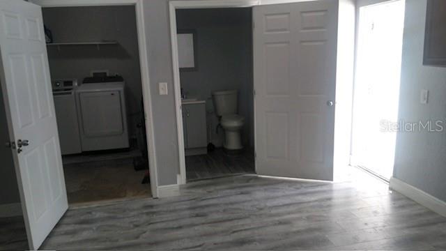 bedroom featuring washer and clothes dryer, connected bathroom, and wood-type flooring