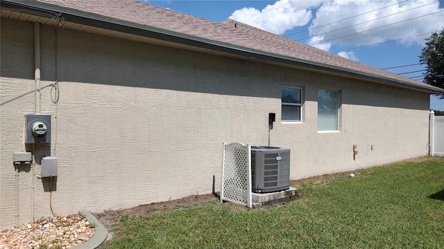 view of side of property with a lawn and cooling unit