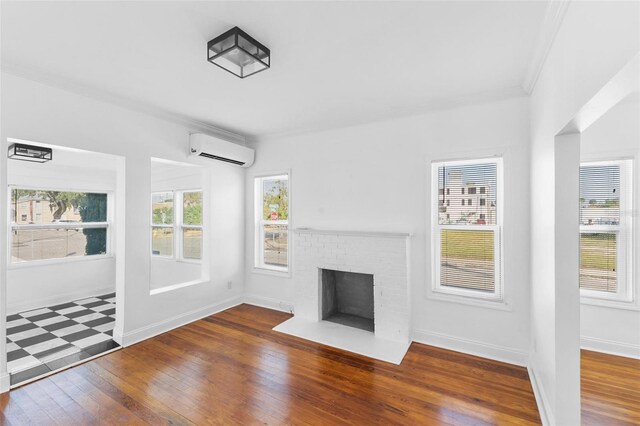 unfurnished living room with wood-type flooring, a fireplace, ornamental molding, and a wall unit AC