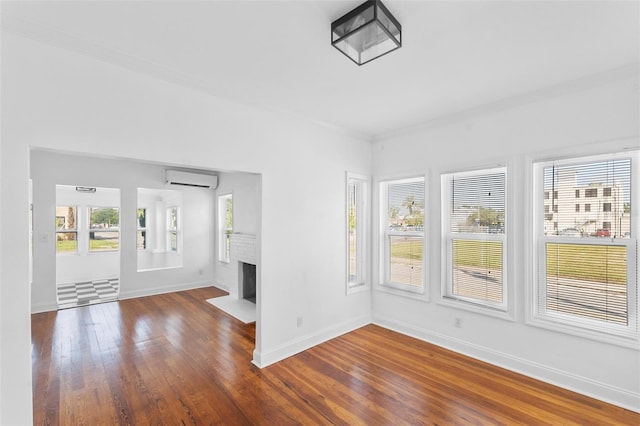 unfurnished living room with ornamental molding, dark wood-type flooring, and a wall mounted air conditioner