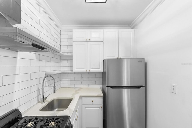 kitchen with white cabinets, sink, range, stainless steel refrigerator, and crown molding