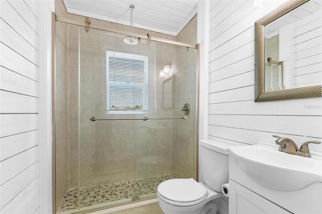 bathroom featuring wood walls, toilet, vanity, and an enclosed shower