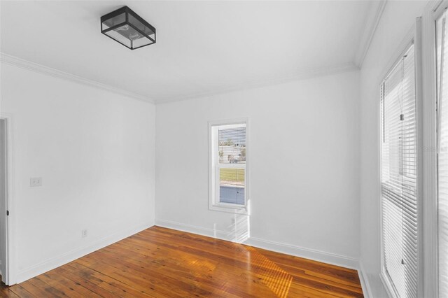 empty room with hardwood / wood-style floors and crown molding