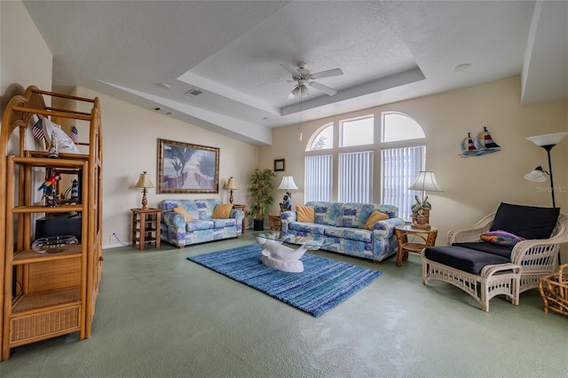 living room with carpet, ceiling fan, a raised ceiling, and a textured ceiling