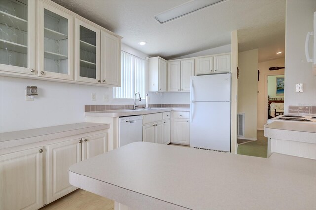 kitchen with white cabinets, lofted ceiling, sink, white appliances, and light hardwood / wood-style flooring