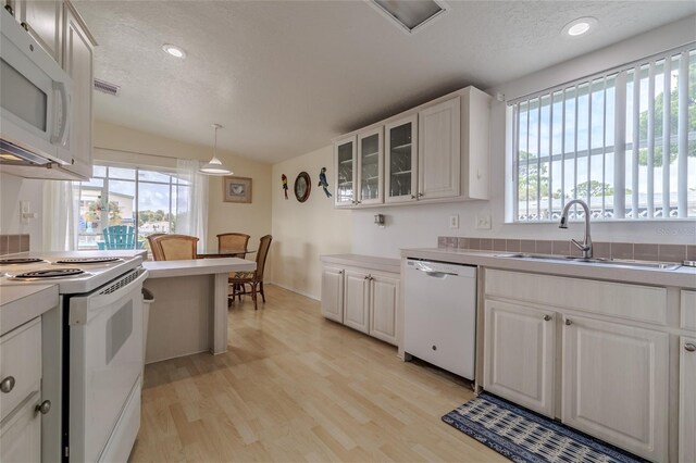 kitchen featuring light wood-type flooring, white cabinetry, vaulted ceiling, hanging light fixtures, and white appliances