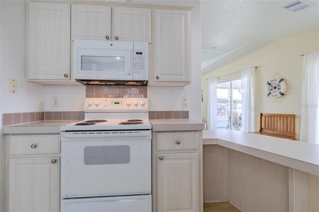 kitchen with a textured ceiling, lofted ceiling, tasteful backsplash, and white appliances