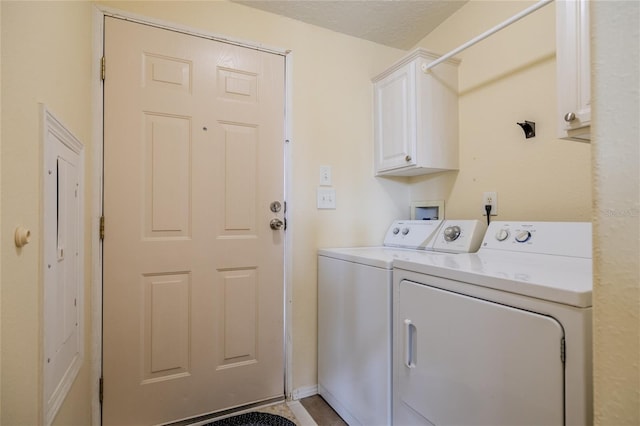 laundry area featuring washer and clothes dryer, cabinets, and a textured ceiling