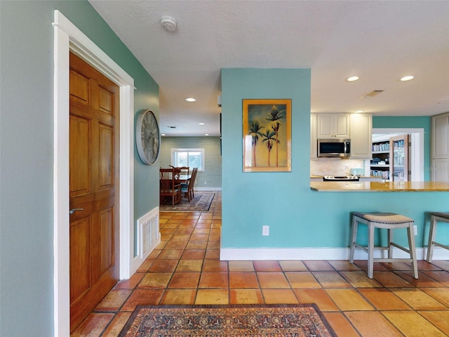 kitchen featuring white cabinets, a kitchen bar, and tile patterned flooring