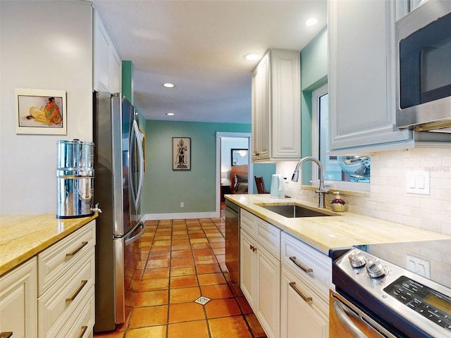 kitchen with white cabinetry, stainless steel appliances, tasteful backsplash, and sink