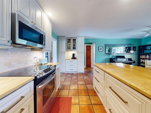 kitchen with tasteful backsplash, white cabinetry, light tile patterned floors, appliances with stainless steel finishes, and ceiling fan