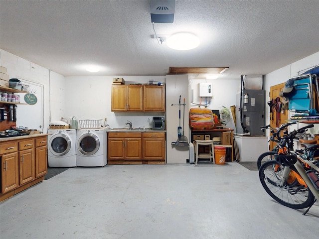 garage with sink, heating unit, and washing machine and clothes dryer