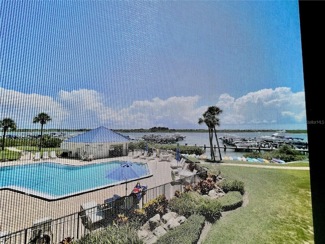 view of pool with a lawn and a water view