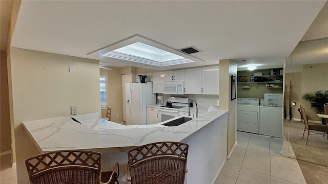 kitchen featuring washing machine and dryer, white cabinets, white appliances, and kitchen peninsula