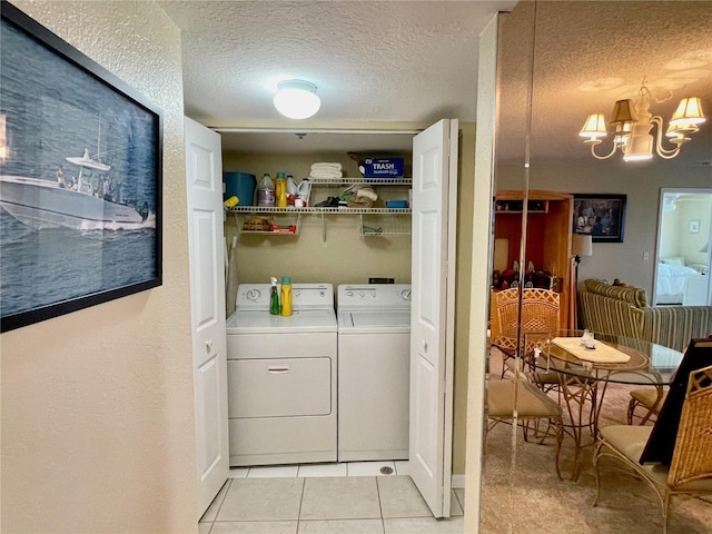 washroom featuring light tile patterned flooring, an inviting chandelier, washing machine and clothes dryer, and a textured ceiling