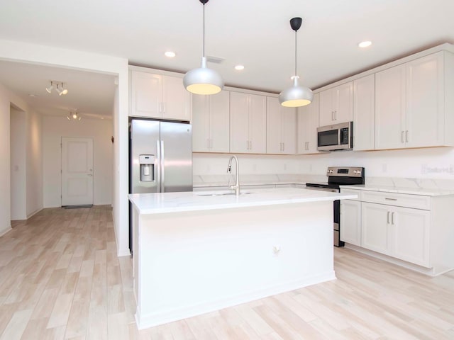 kitchen with appliances with stainless steel finishes, white cabinetry, sink, and light hardwood / wood-style flooring