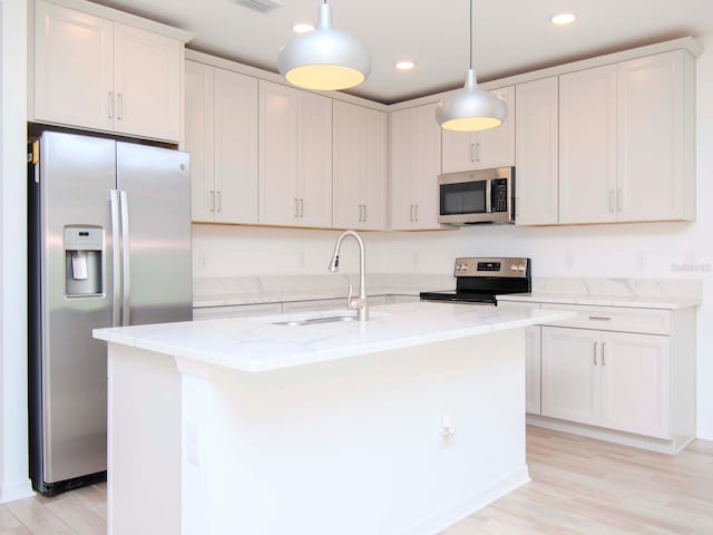 kitchen with white cabinets, a kitchen island with sink, and stainless steel appliances