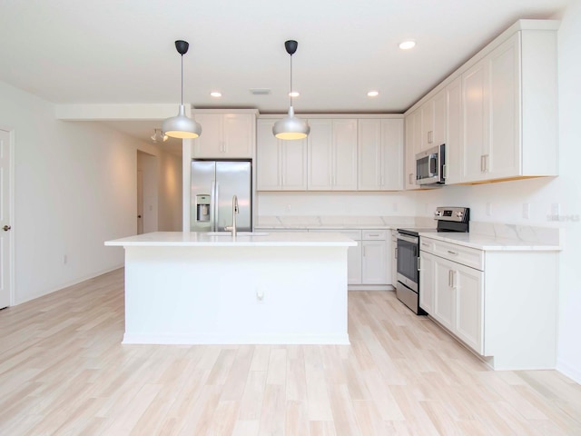 kitchen with light hardwood / wood-style floors, pendant lighting, stainless steel appliances, and white cabinets