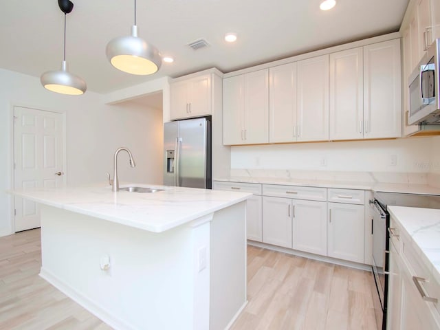 kitchen featuring a center island with sink, sink, stainless steel appliances, and white cabinets