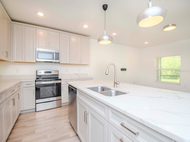 kitchen with pendant lighting, stainless steel appliances, white cabinetry, and sink