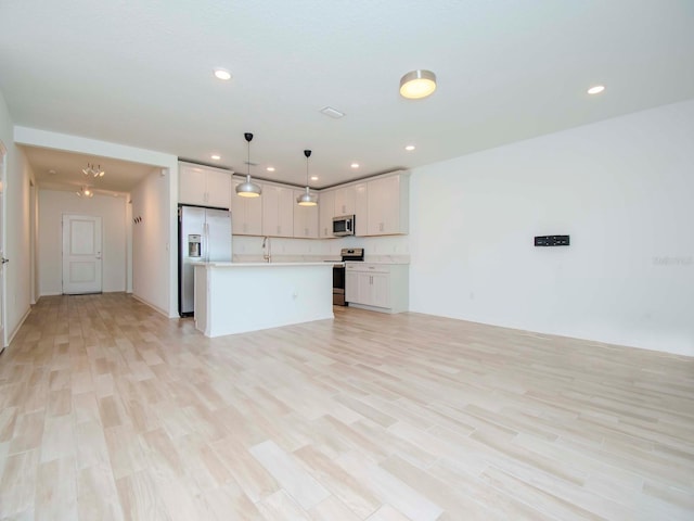 kitchen featuring appliances with stainless steel finishes, light hardwood / wood-style floors, white cabinetry, a center island, and decorative light fixtures