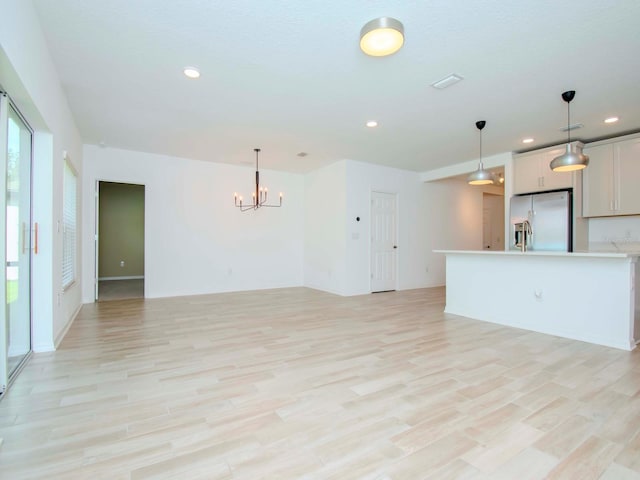 unfurnished living room featuring light hardwood / wood-style flooring and a notable chandelier