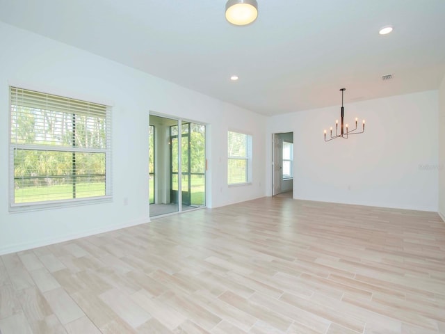 unfurnished living room featuring light wood-type flooring and an inviting chandelier