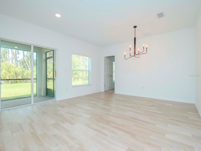 unfurnished room featuring light wood-type flooring and a notable chandelier