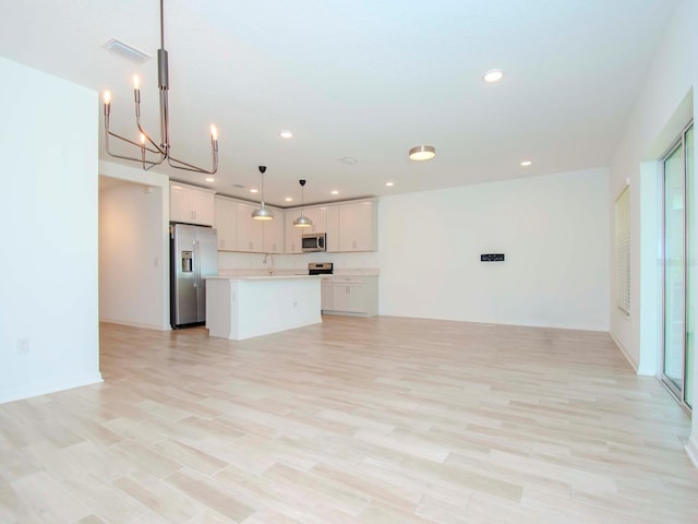 kitchen with light hardwood / wood-style floors, white cabinetry, hanging light fixtures, a kitchen island, and appliances with stainless steel finishes