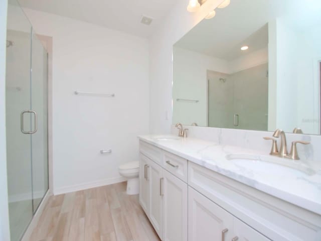 bathroom with a shower with door, toilet, vanity, and hardwood / wood-style flooring