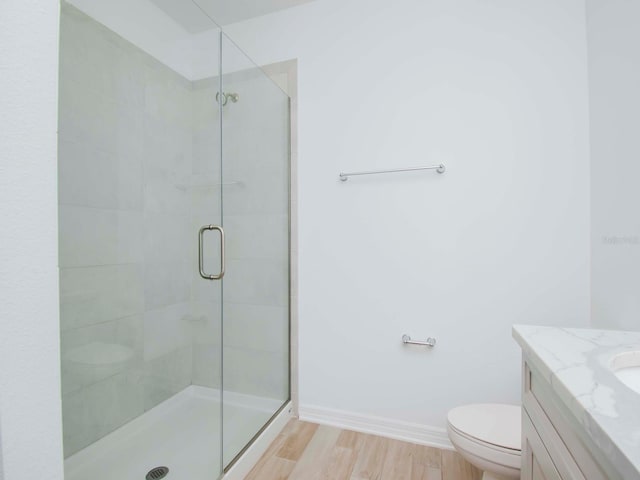 bathroom with vanity, hardwood / wood-style floors, toilet, and a shower with shower door