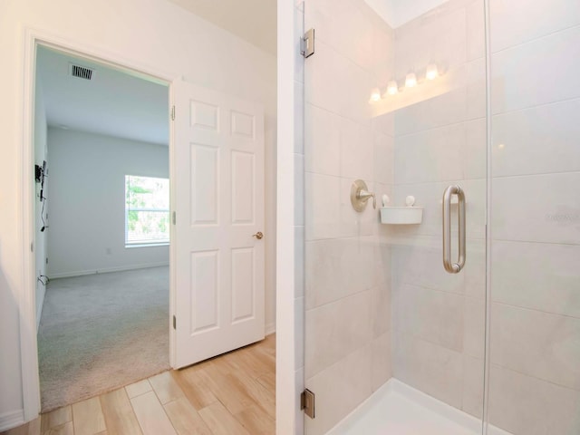 bathroom with wood-type flooring and a shower with door