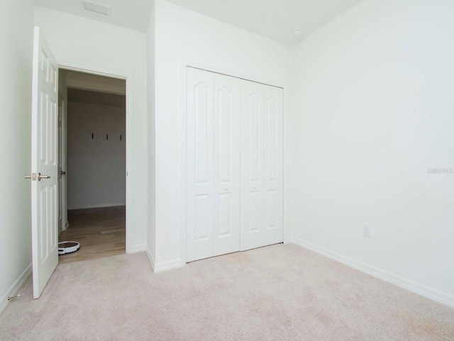 unfurnished bedroom with light carpet and a closet