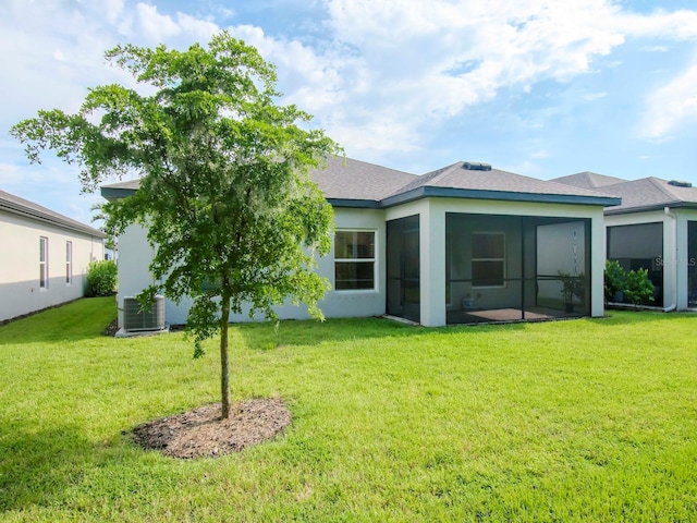 back of property with a sunroom, a yard, and central AC